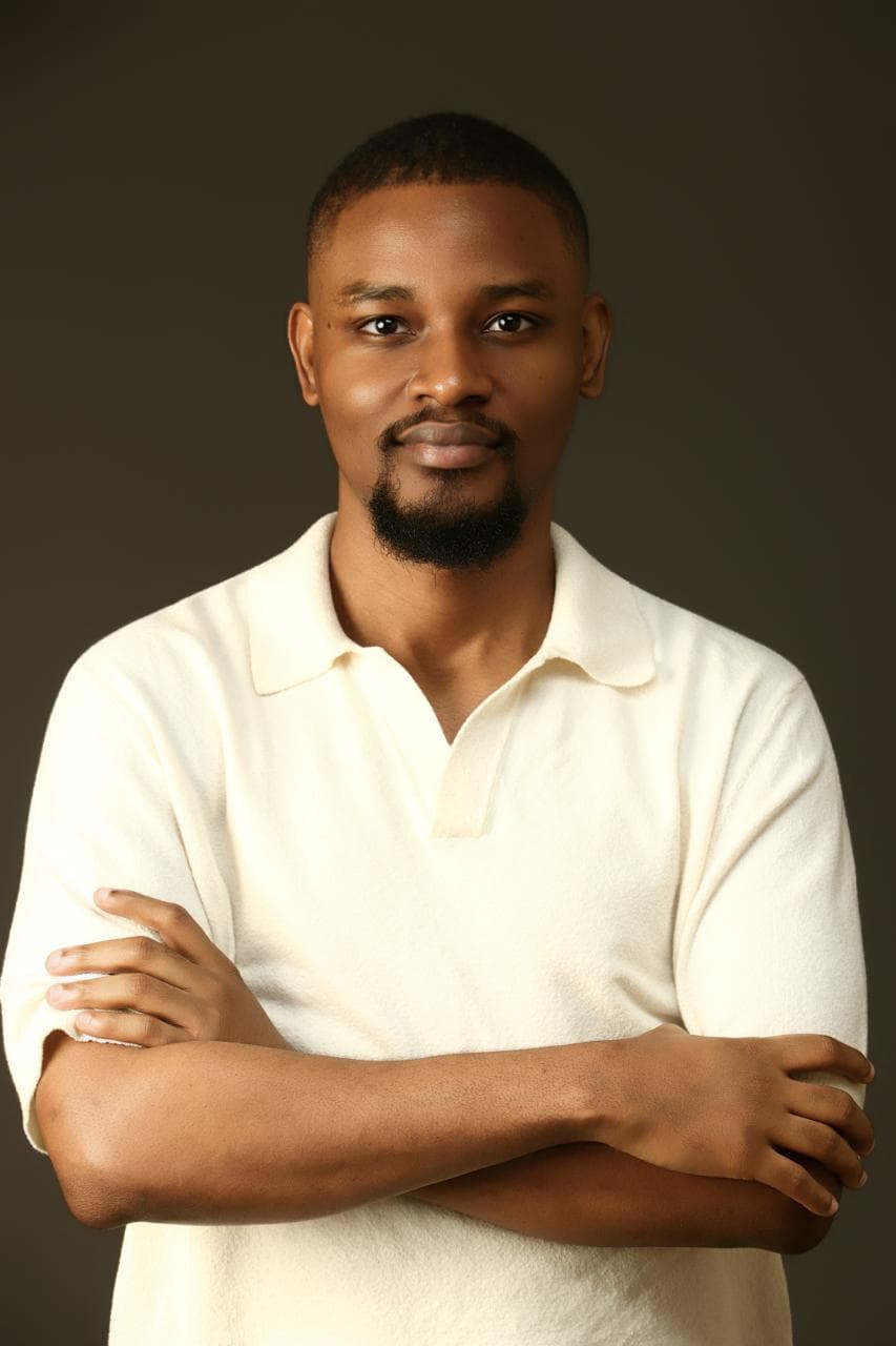 Kehinde Abiuwa in a cream polo with his arms folded
